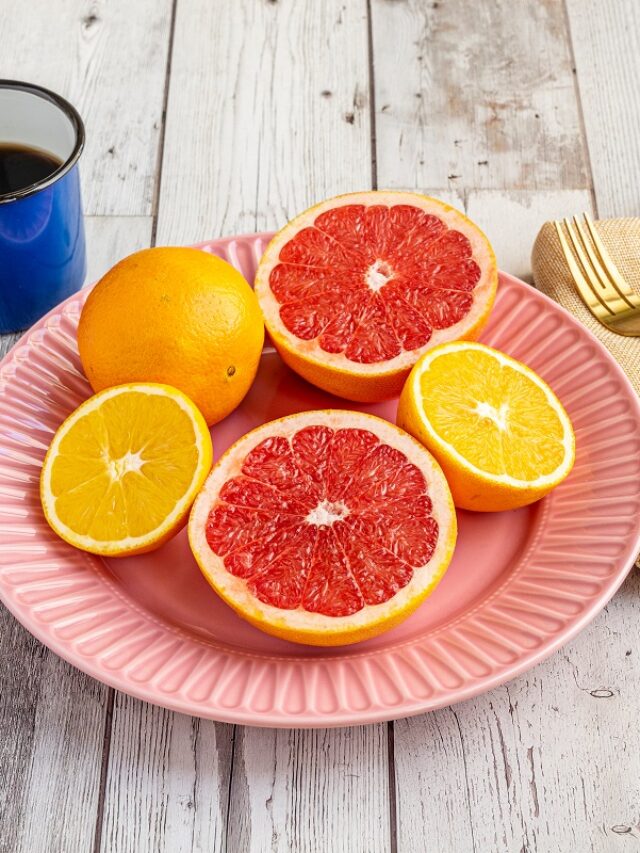 Plate of halved citrus fruits, oranges and grapefruits with coff