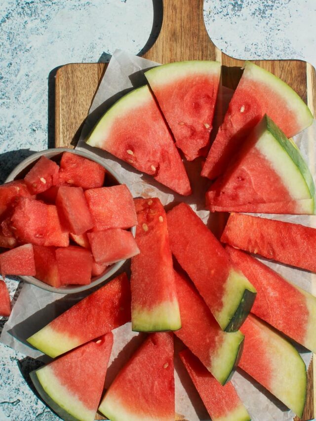 Watermelon-cut-into-triangles-sticks-and-cubes-on-a-cutting-board