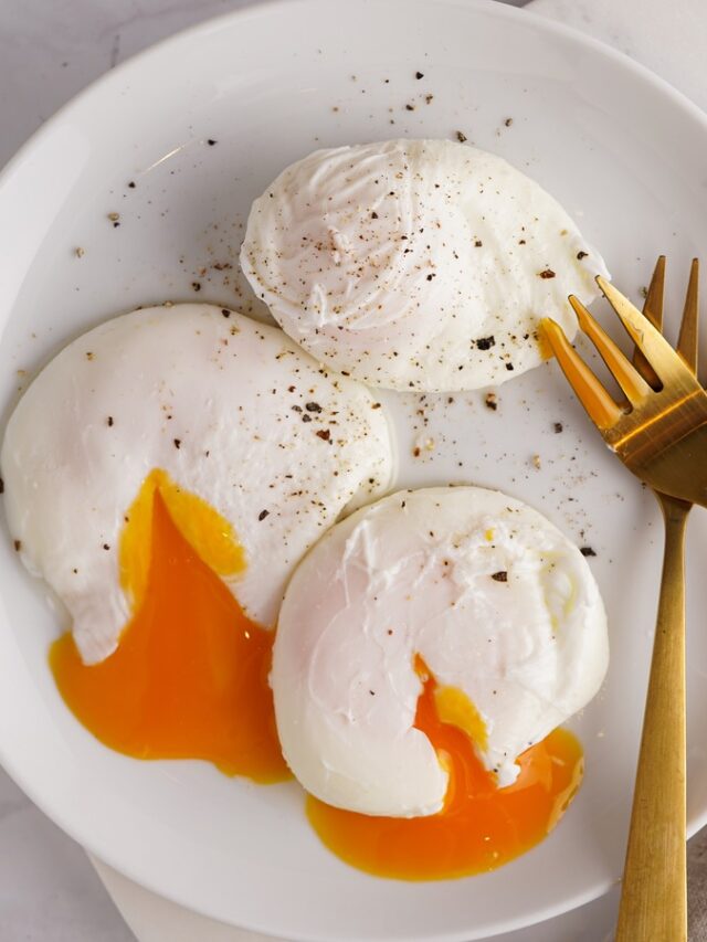Three,Poached,Eggs,With,Egg,Yolk,On,A,White,Plate